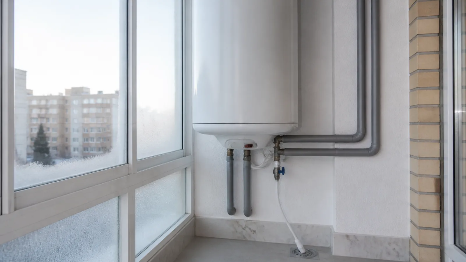 Termo eléctrico recién instalado en una galería acristalada con tuberías aisladas contra las heladas
